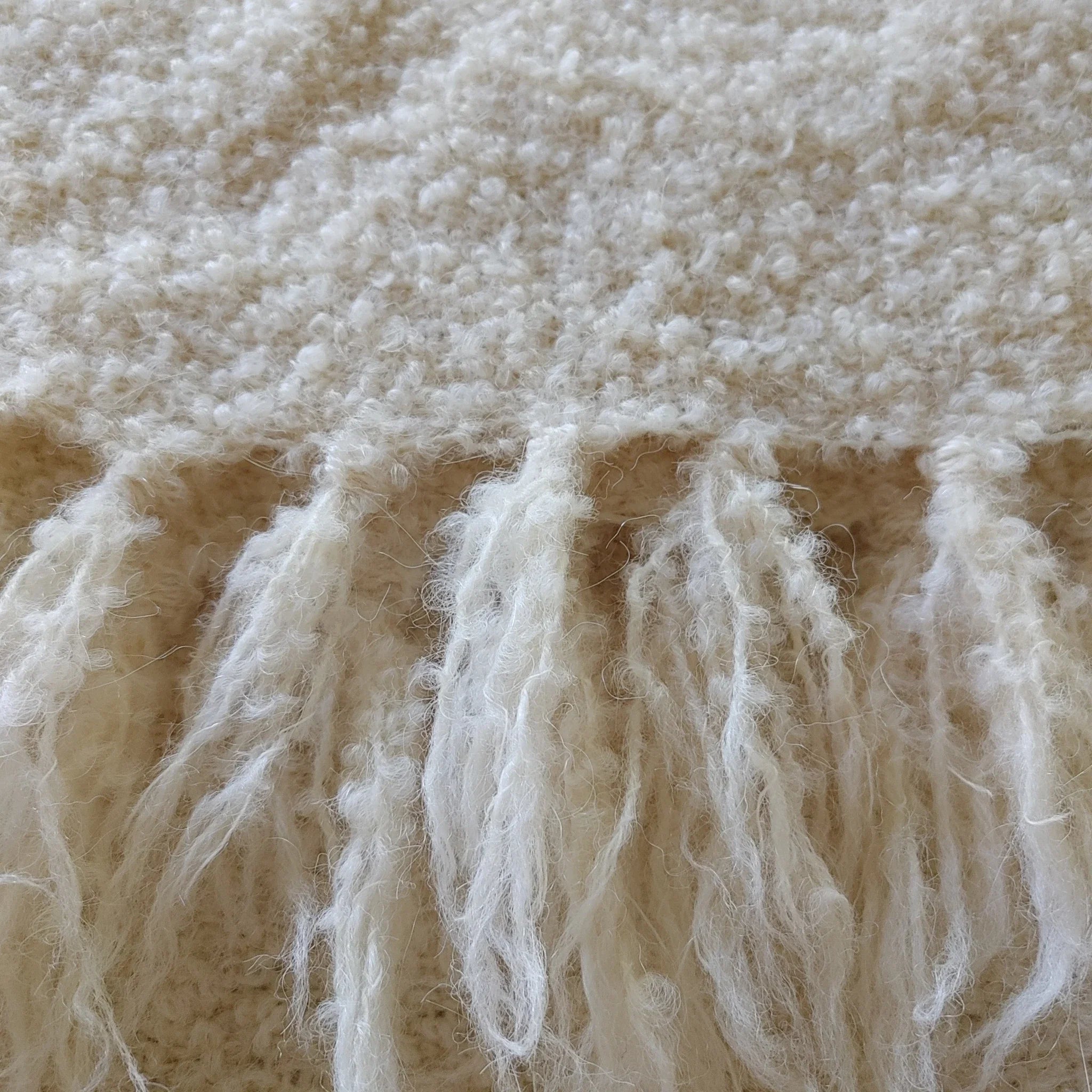 Hand-tied fringe detail on natural white alpaca loop yarn throw