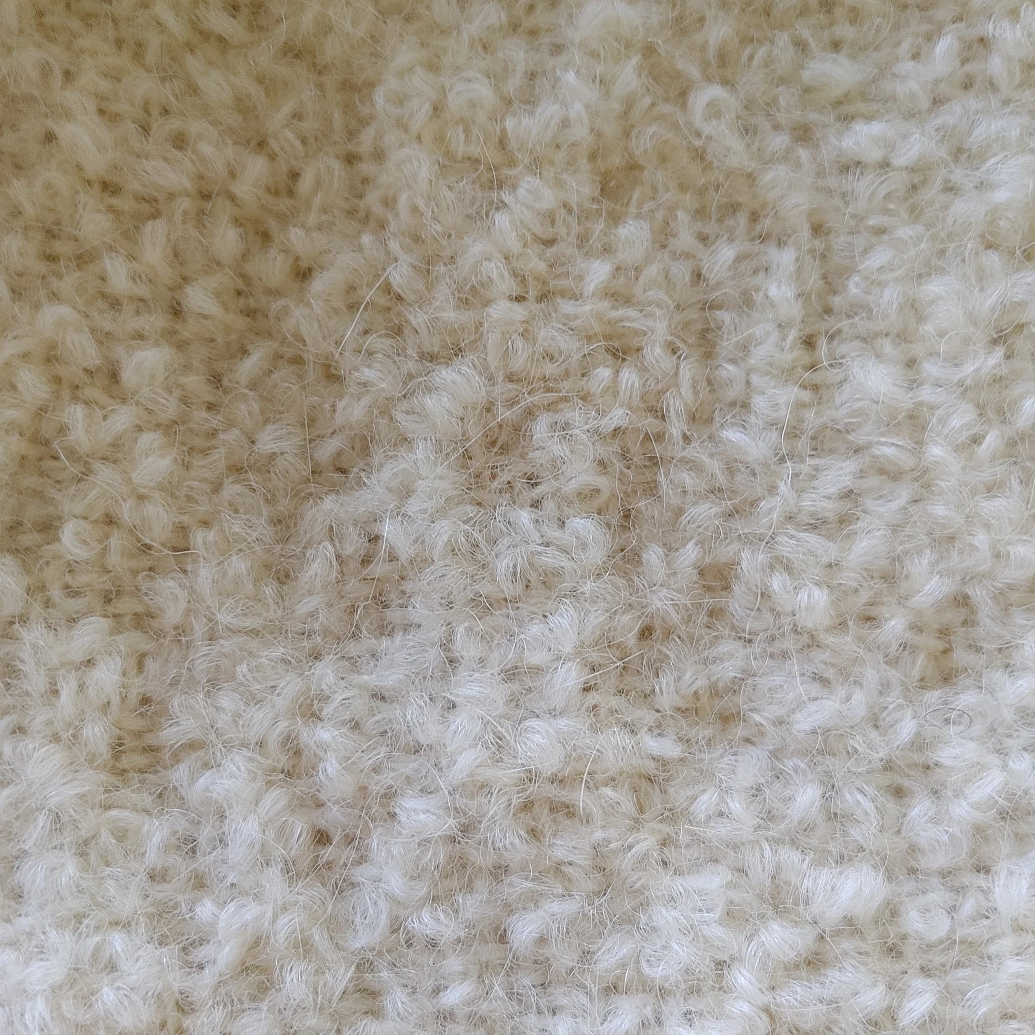 Close-up of curly boucle loop yarn texture on natural white alpaca throw