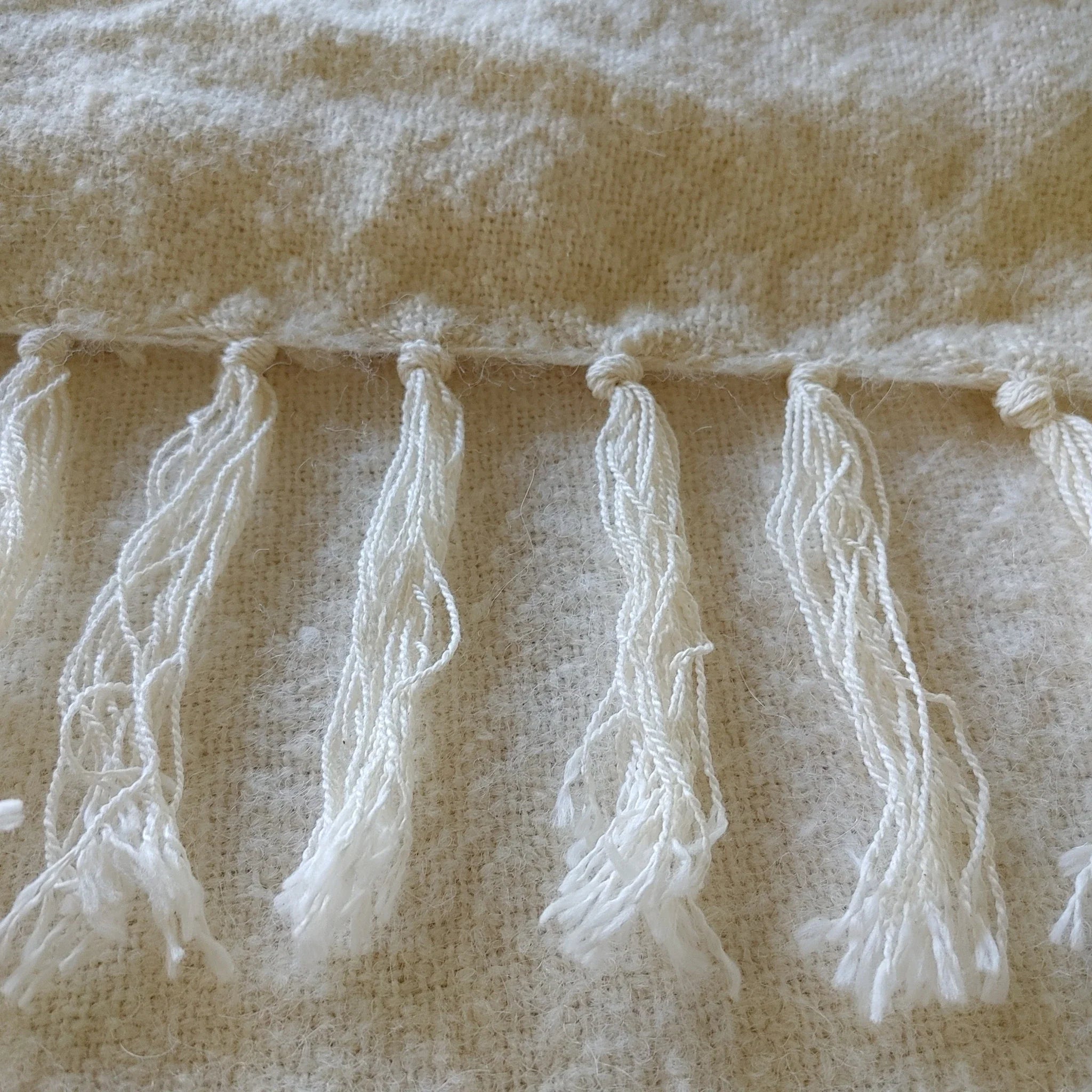 Flat weave texture and hand-finished fringe edge of natural white alpaca silk throw