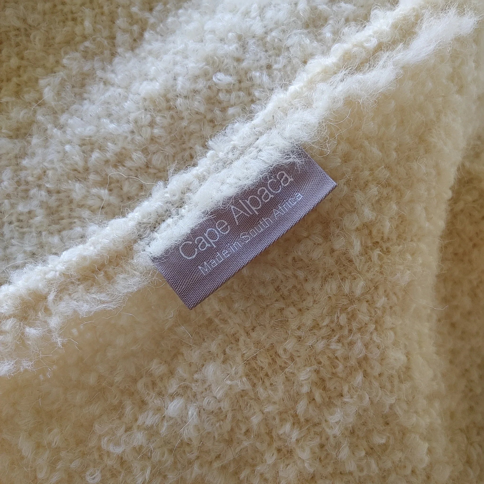 Close-up of Cape Alpaca woven label on natural white loop yarn alpaca throw