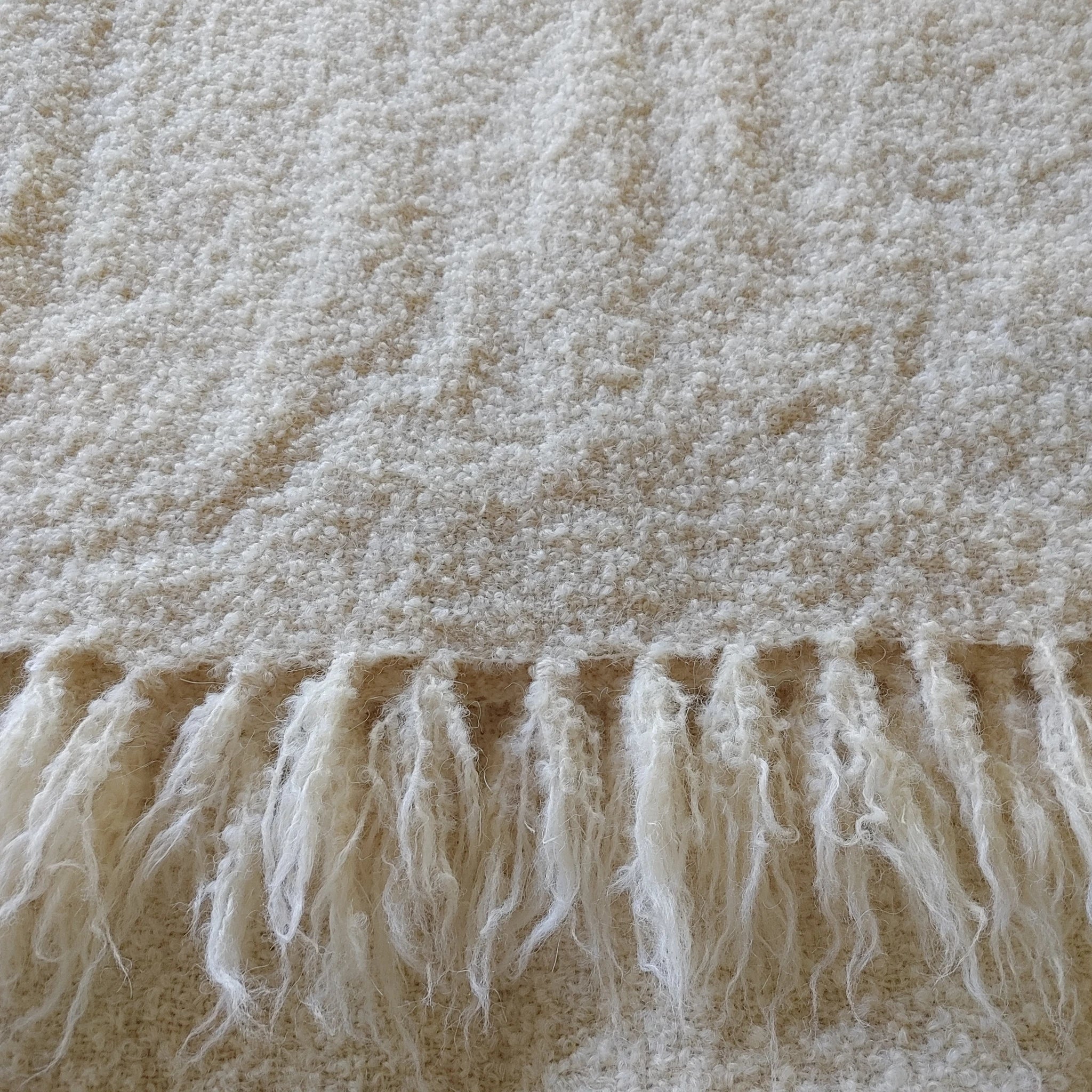 Boucle texture and hand-finished fringe edge of natural white alpaca loop yarn throw