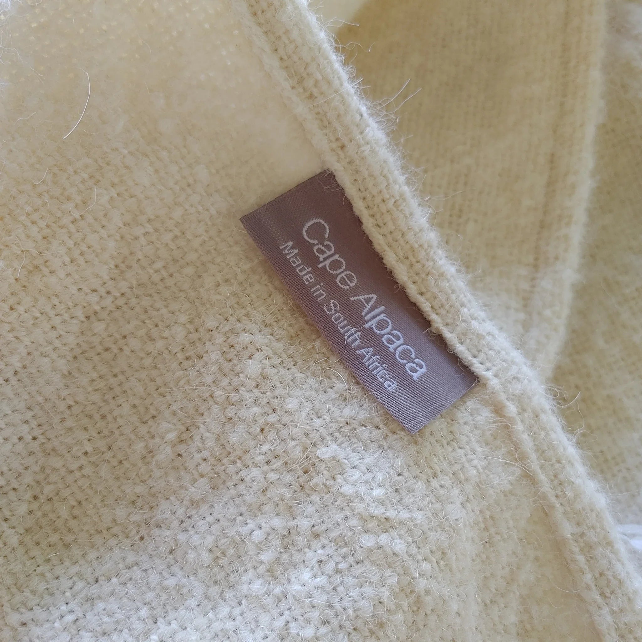 Close-up of Cape Alpaca woven label on natural white alpaca silk throw
