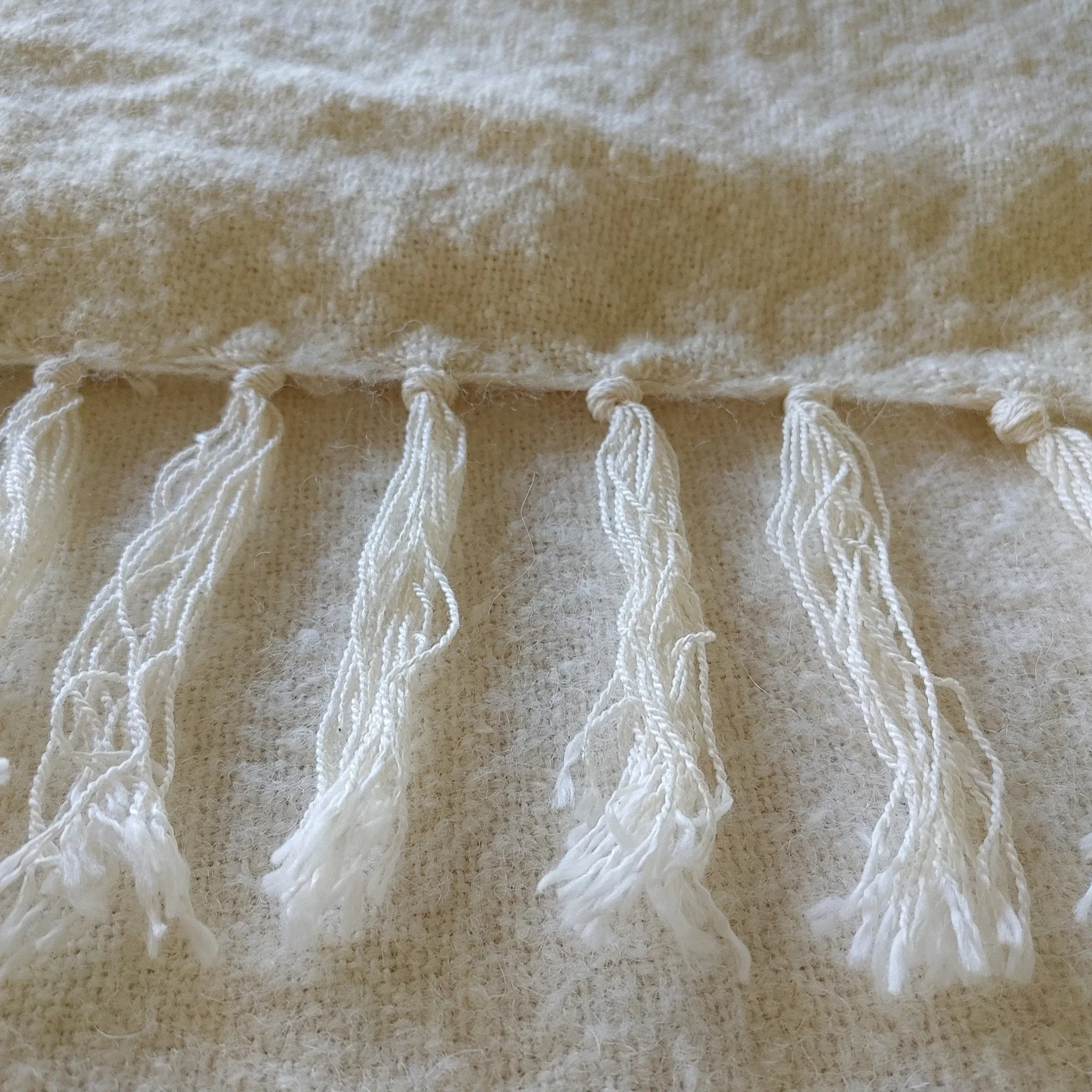 Hand-tied fringe detail on natural white alpaca silk throw
